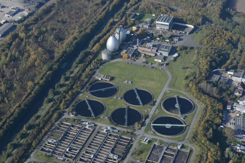 Aerial photograph of a wastewater treatment plant surrounded by autumn trees, showcasing ecological and industrial elements.